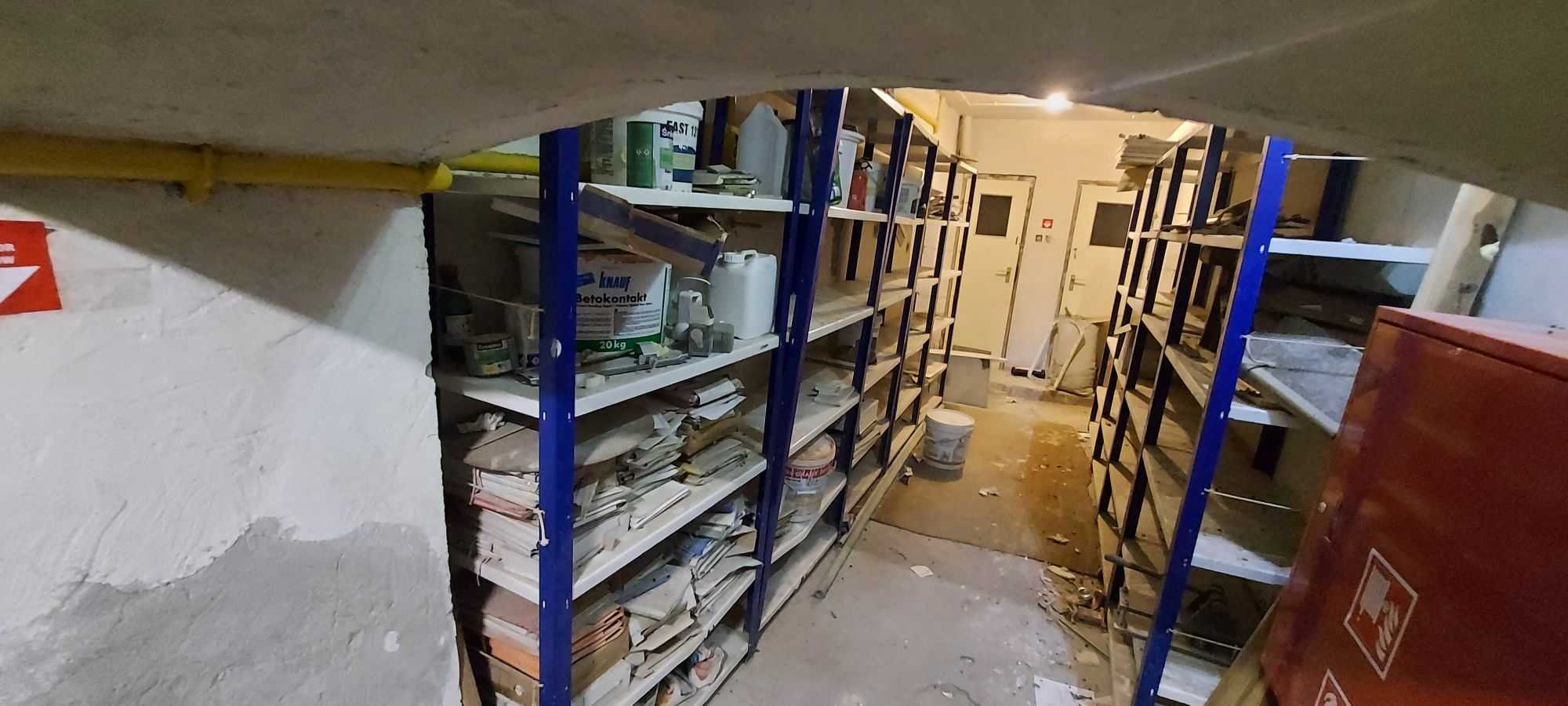 Zagracony magazyn w piwnicy z metalowymi regałami pełnymi dokumentów i śmieci - Warszawa